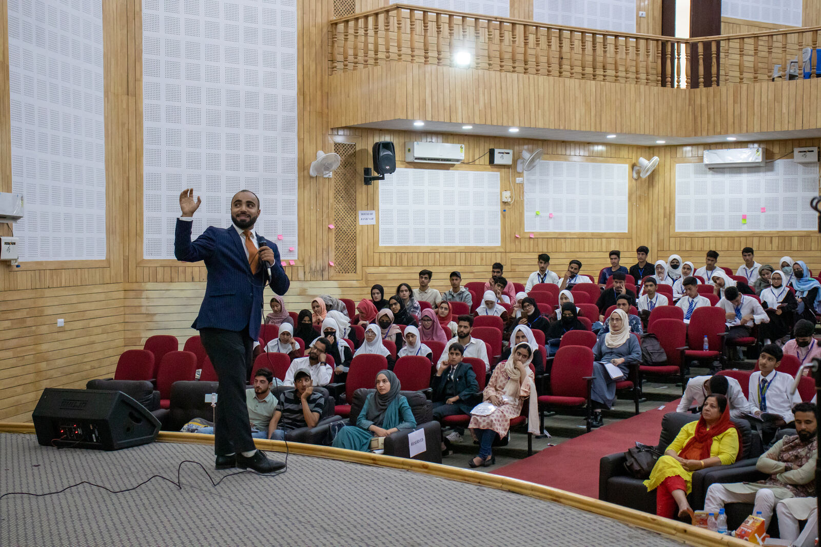 Farhat Umar on stage addressing a full university auditorium