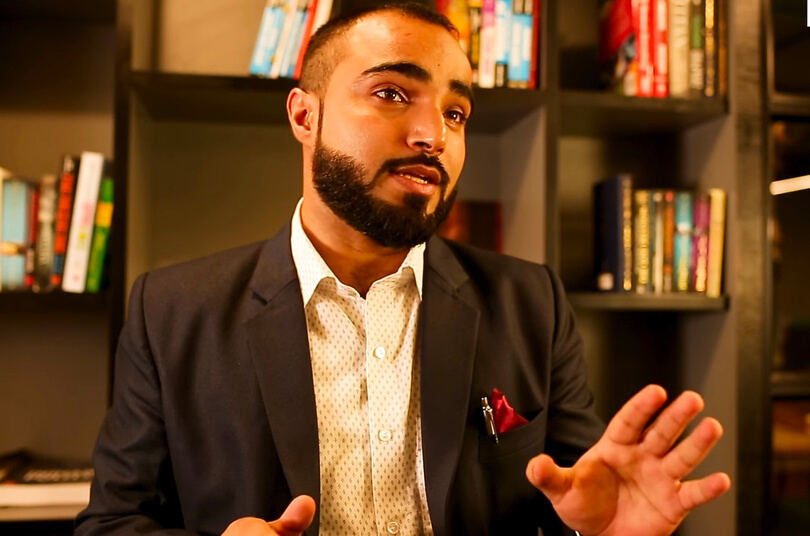 Farhat speaking in front of a bookshelf
